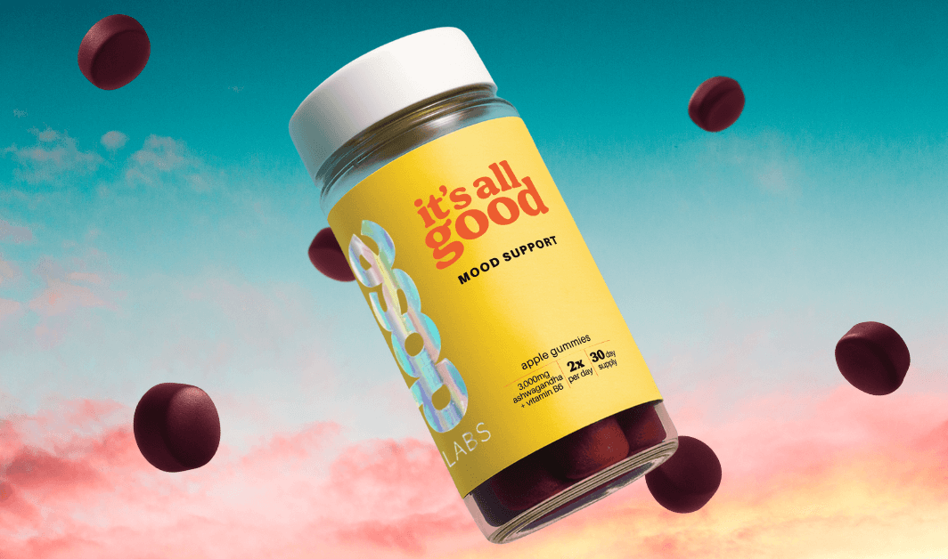 Jars of 'it's all good' mood support supplement on an orange background with scattered gummies